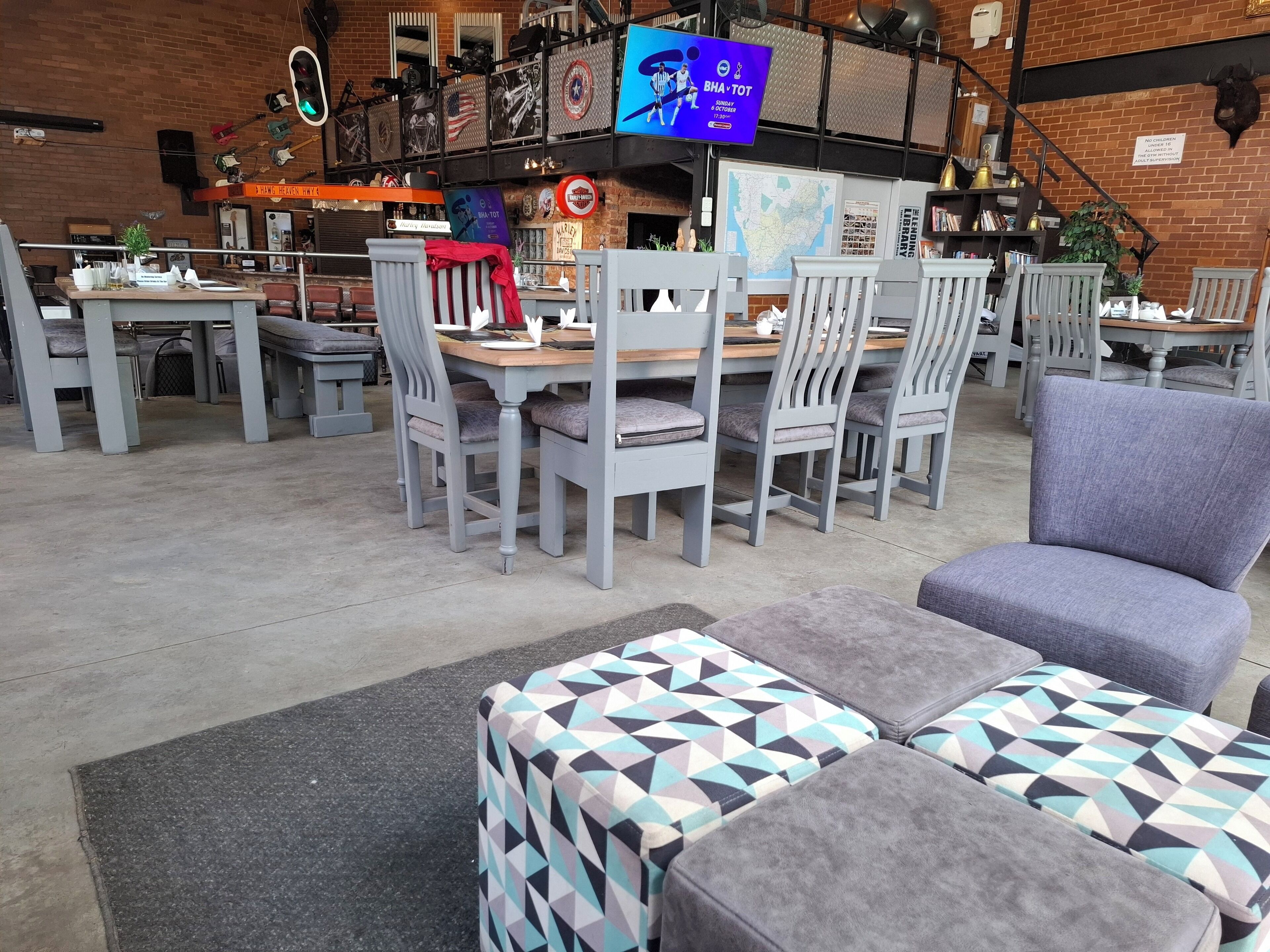 A restaurant with multiple tables and chairs, a television screen, and various decorations on the walls.