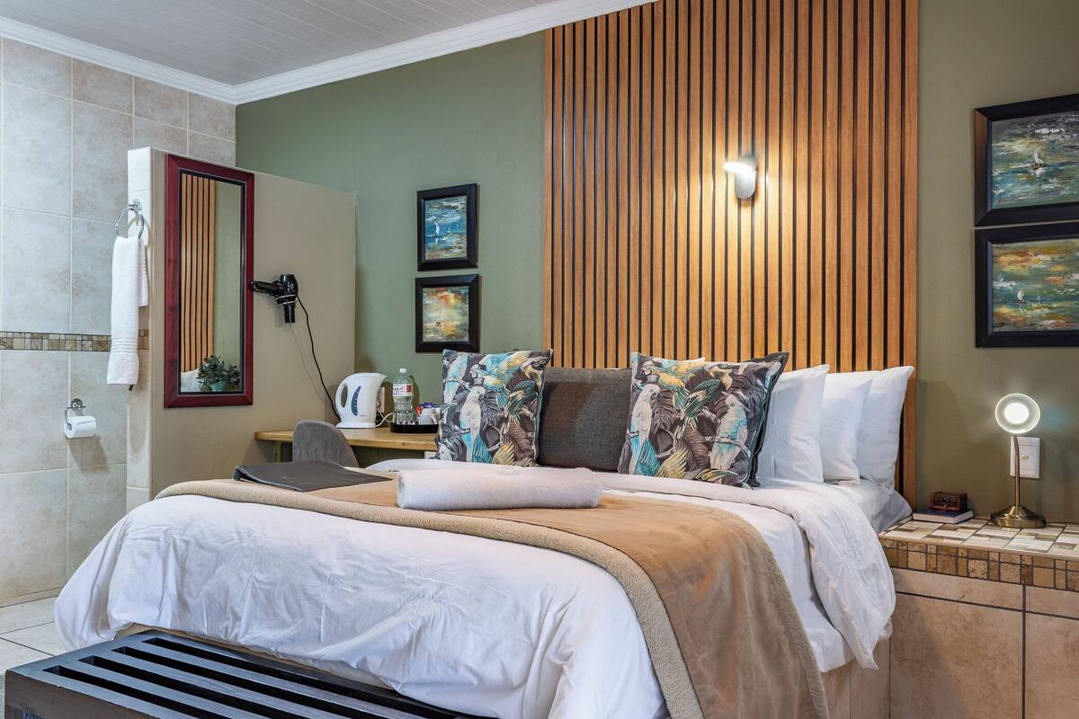 A well-appointed bedroom with a large bed, a bedside table, a mirror, and artwork on the wall.