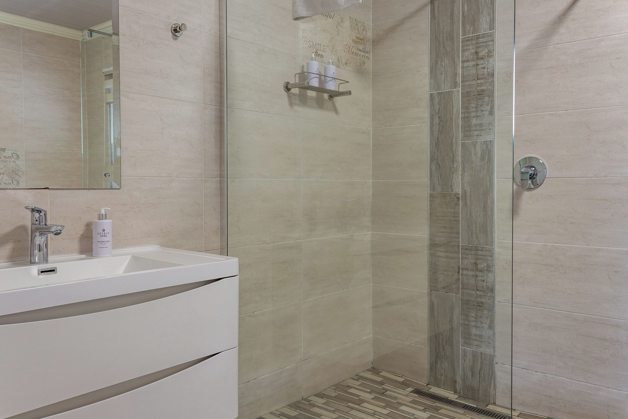 A modern bathroom with a white sink, a mirror, and a shower with a glass door.