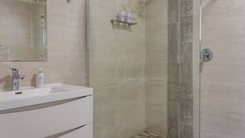 A modern bathroom with a white sink, a mirror, and a shower with a glass door.