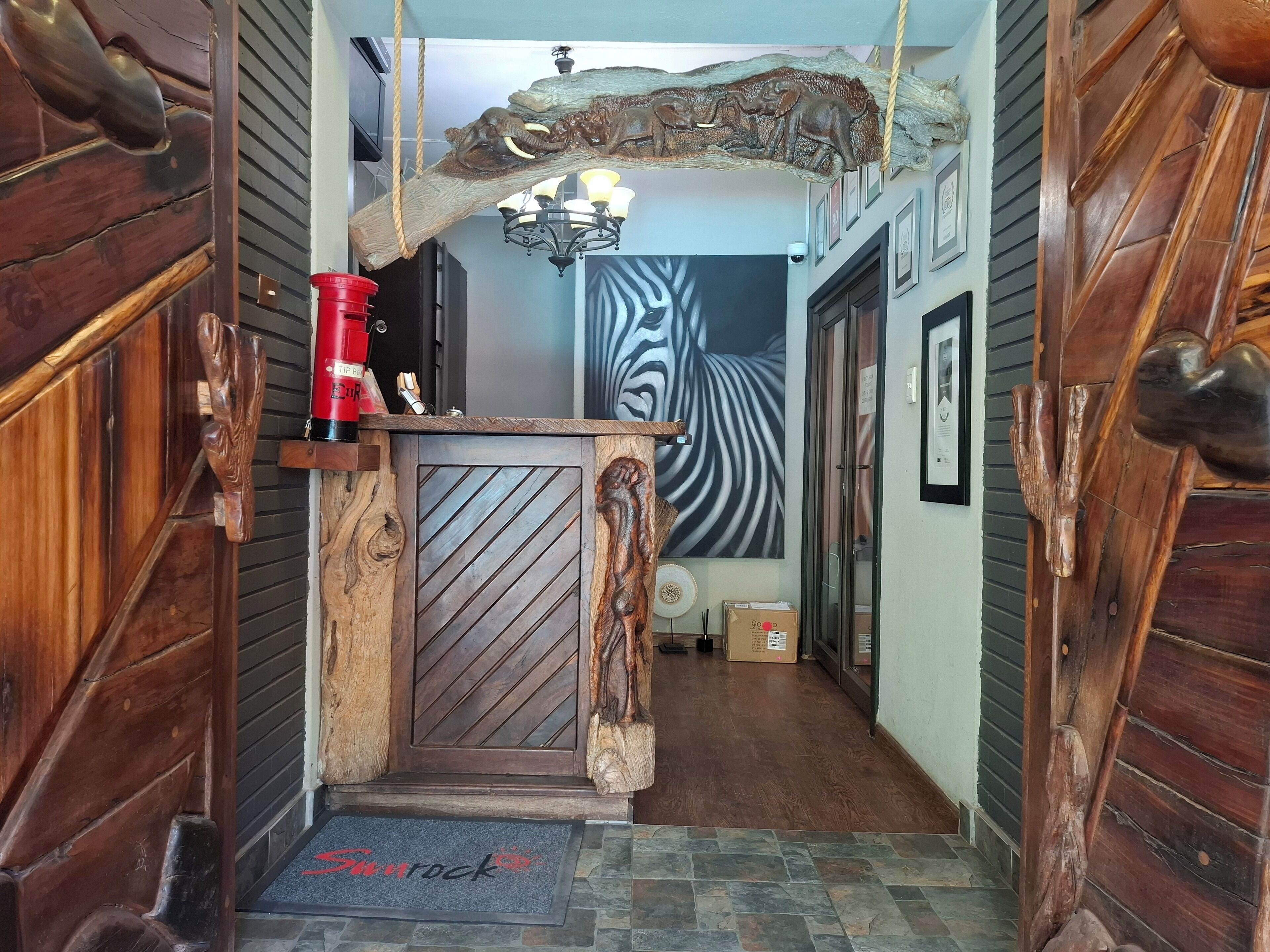 A wooden interior with a central door, a chandelier, and a zebra-striped wall.
