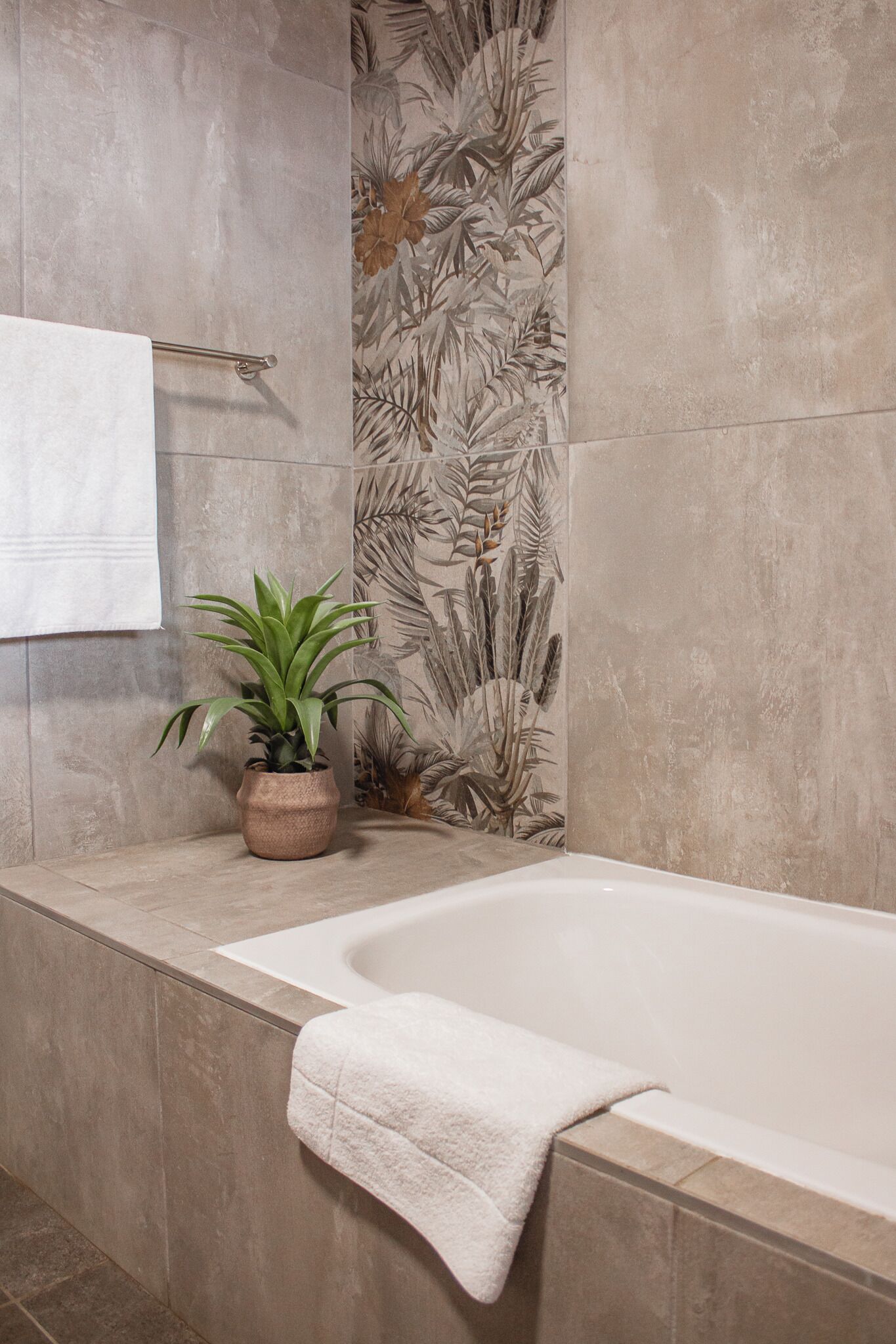 Um banheiro com banheira, porta-toalhas e um vaso de planta.
