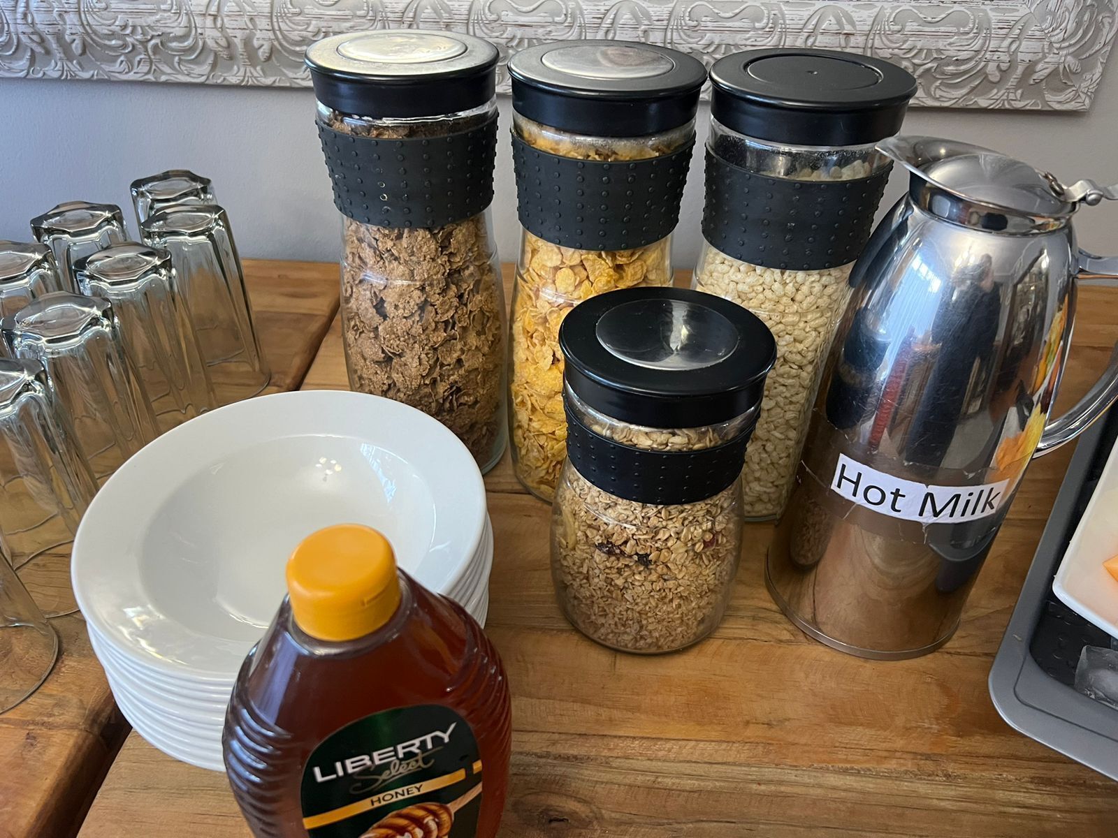 A kitchen counter with various food items and containers, including jars of grains and a bottle of honey.