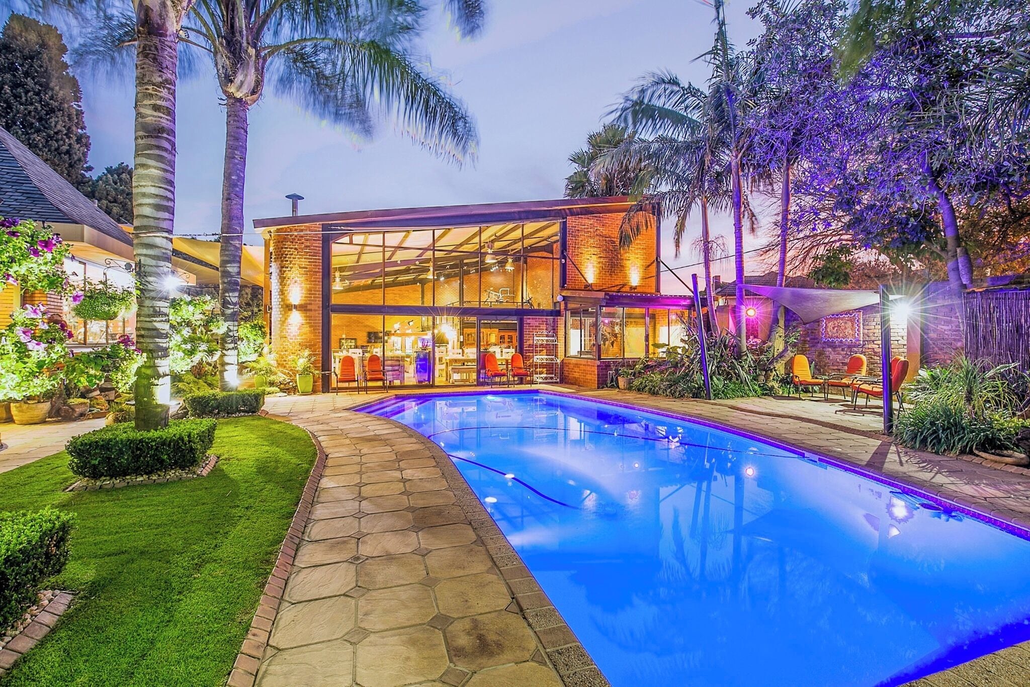 A modern building with a glass facade, a swimming pool, and outdoor seating.