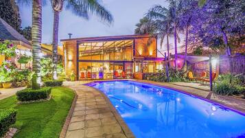 A modern building with a glass facade, a swimming pool, and outdoor seating.
