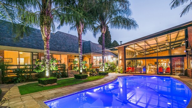 A modern house with a swimming pool, large windows, and a well-maintained garden. - Sunrock Guesthouse (Kempton Park)