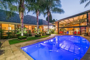 Ein modernes Haus mit Swimmingpool, großen Fenstern und einem gepflegten Garten.