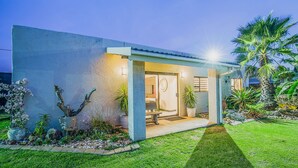 A modern house with a well-maintained lawn, potted plants, and a patio area. - Sunrock Guesthouse (Kempton Park)