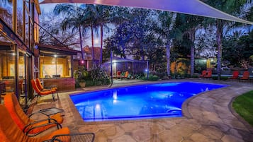 Una piscina al aire libre, sombrillas, sillones reclinables de piscina
