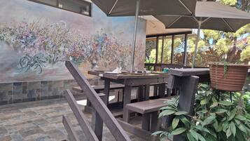 A patio area with a mural of flowers, outdoor seating, and a stone-tiled floor.