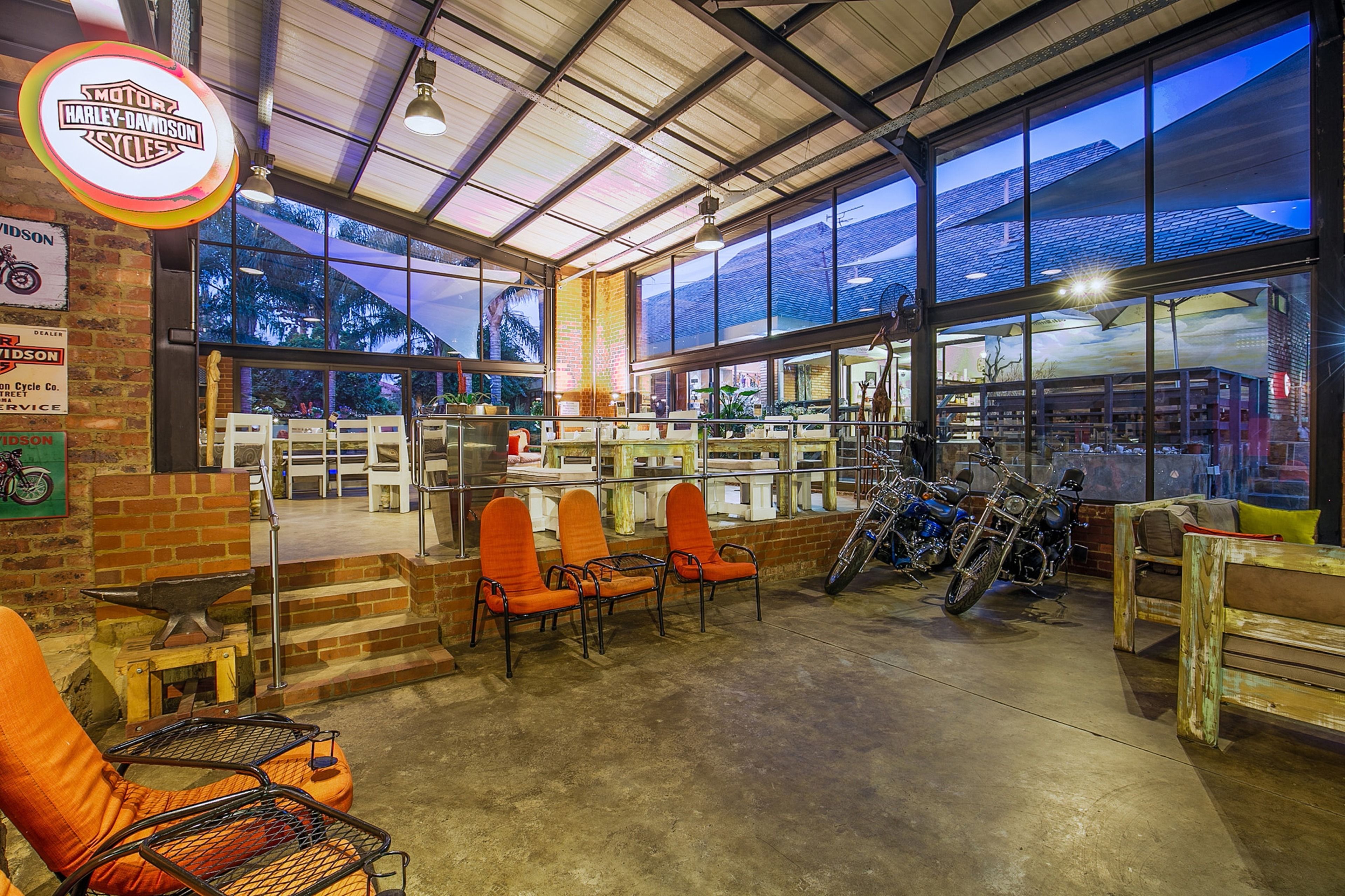 A motorcycle shop interior with seating, bikes, and a large window view.