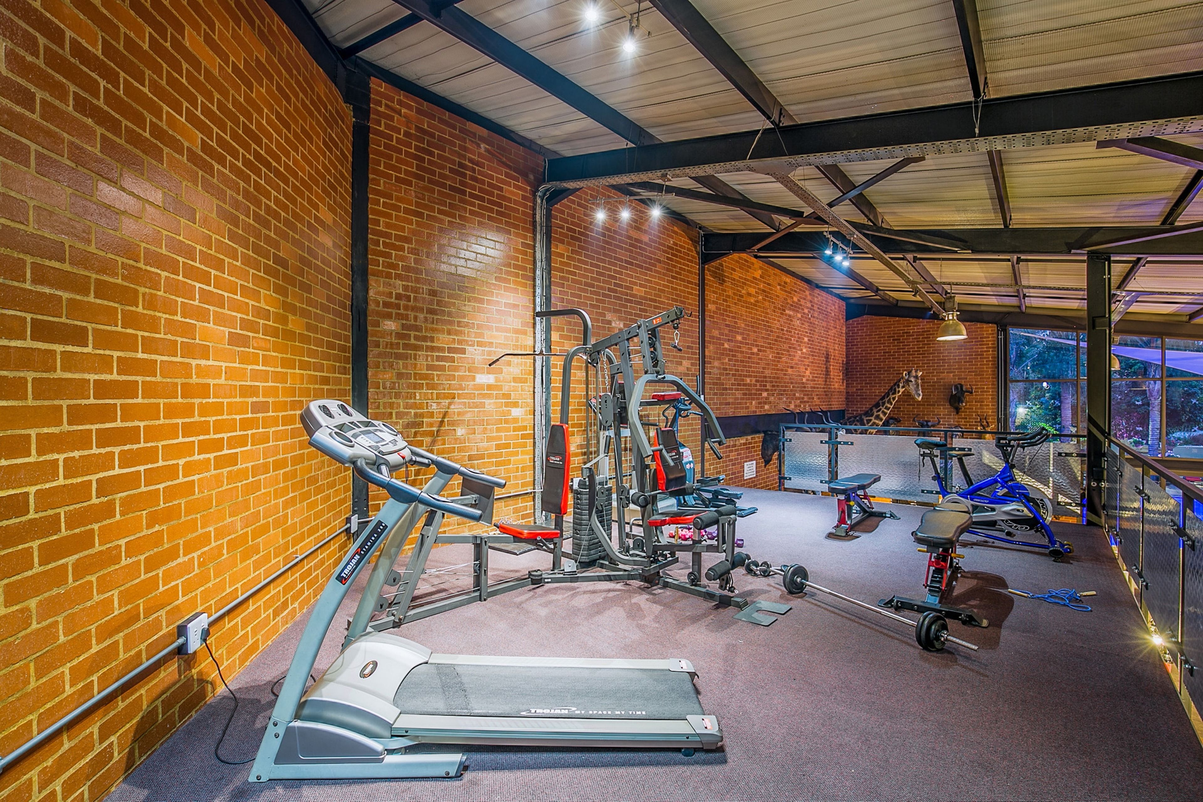 A gym with exercise equipment, a treadmill, and a brick wall.