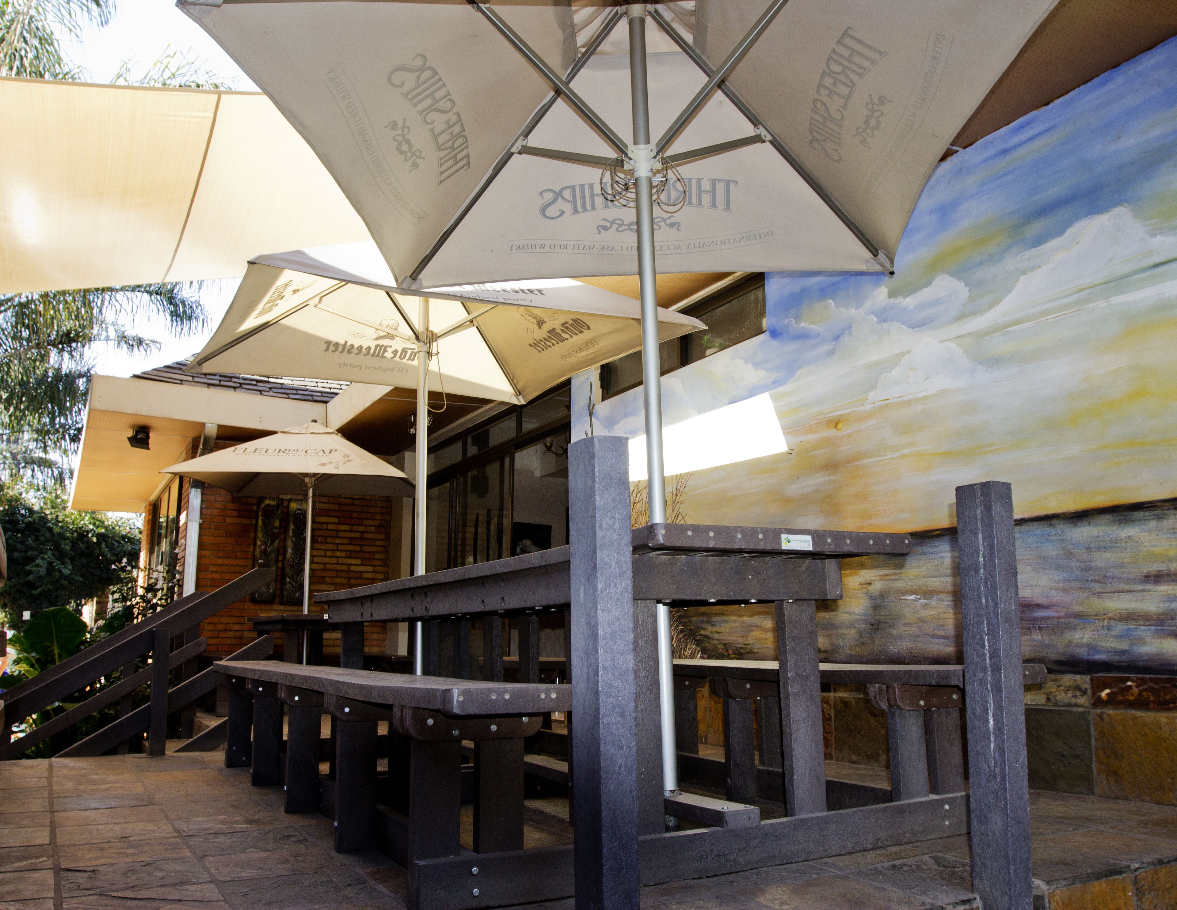 Outdoor seating with umbrellas, a staircase, and a mural on the wall.