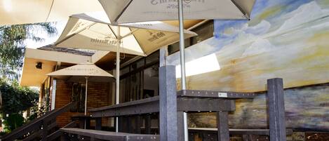 Outdoor seating with umbrellas, a staircase, and a mural on the wall.