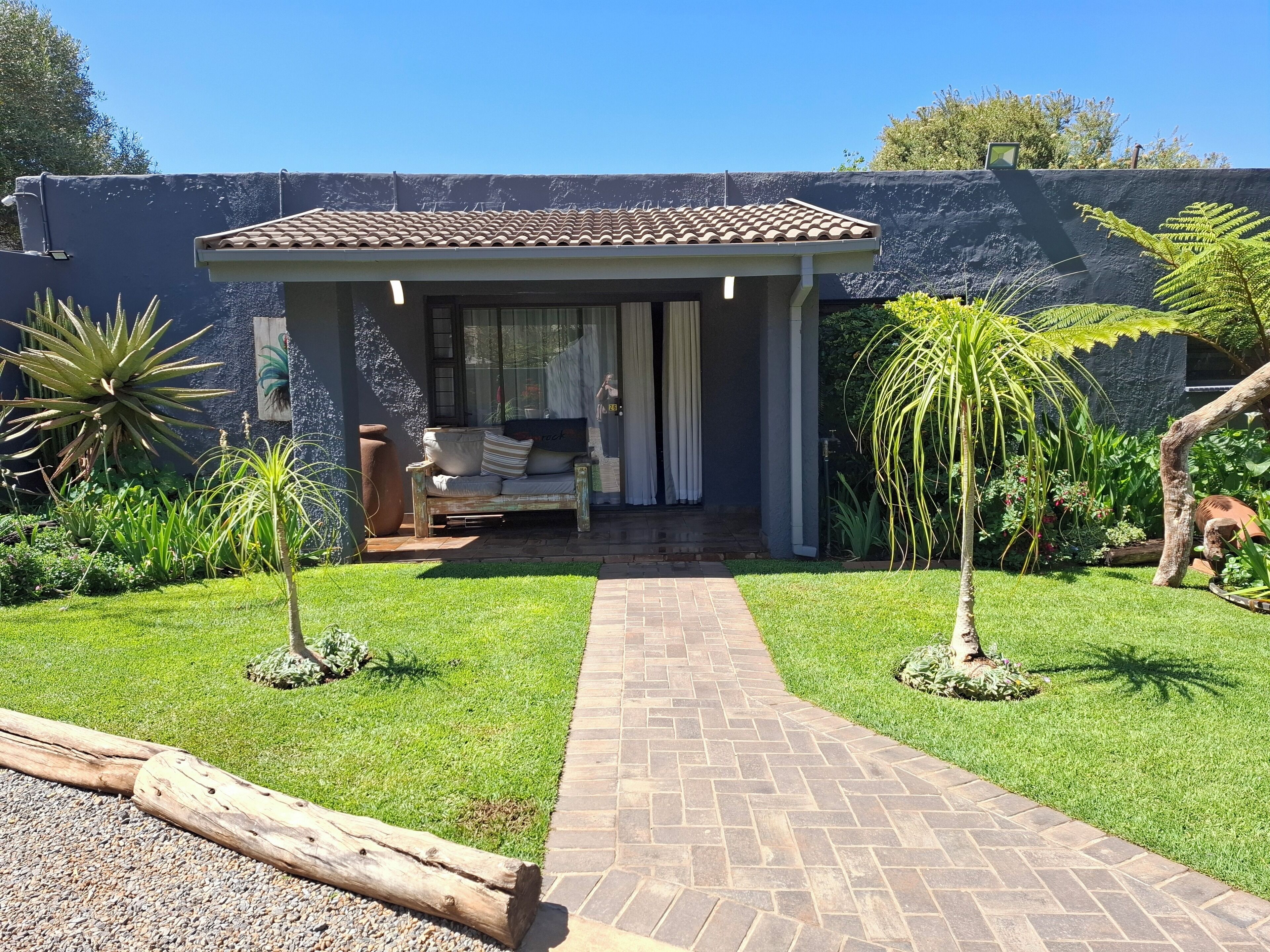 Une maison dotée d’un patio, d’un petit jardin et d’un chemin menant à l’entrée.