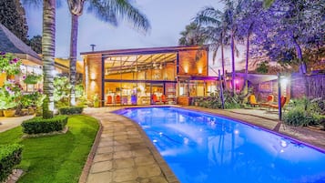 Relax by the pool surrounded by lush greenery and palm trees.