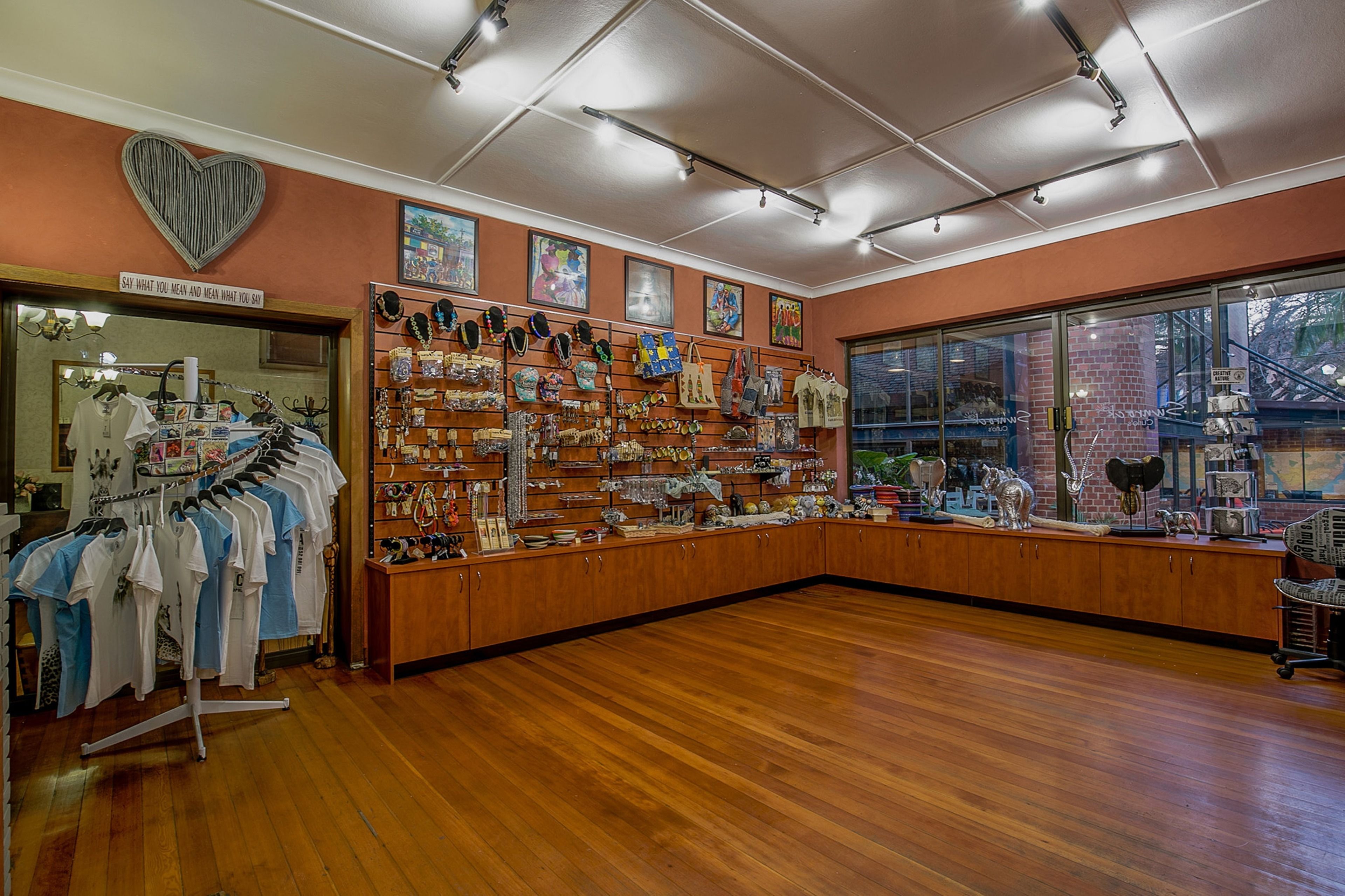 A boutique store with wooden flooring, a heart-shaped sign, and various items on display.
