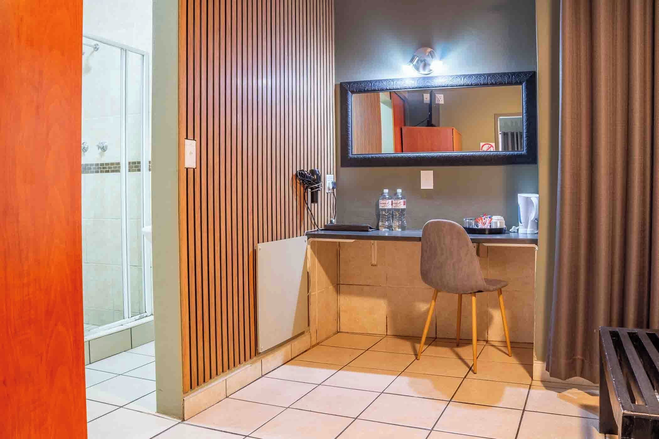 Una habitación compacta con kitchenette, un espejo, una silla y una pequeña mesa.