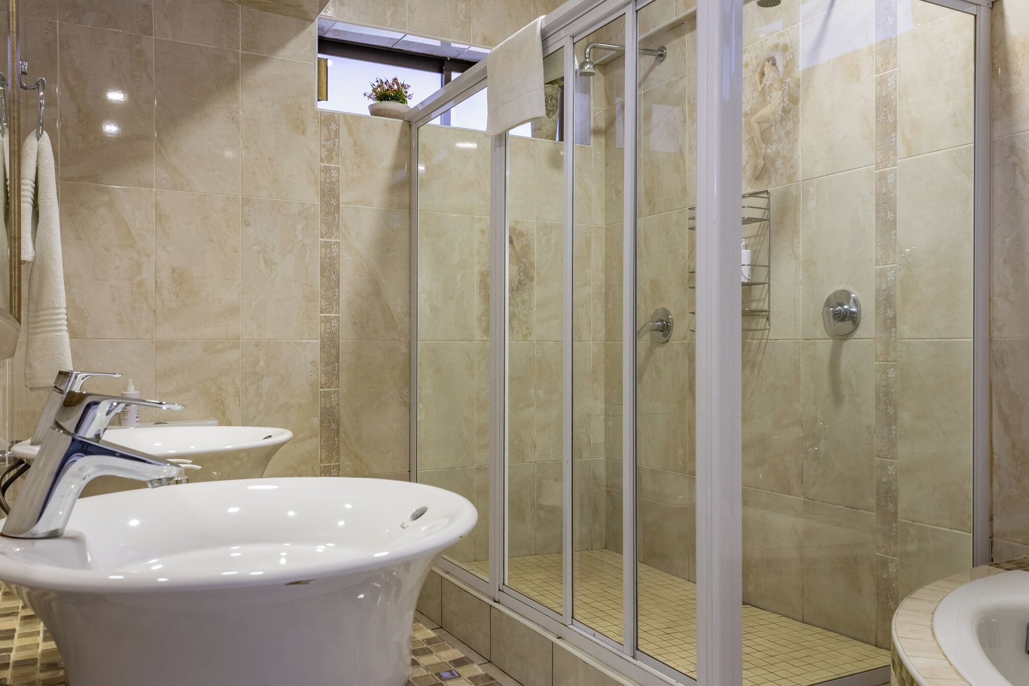 A modern bathroom with a freestanding bathtub, a glass-enclosed shower, and a small sink.