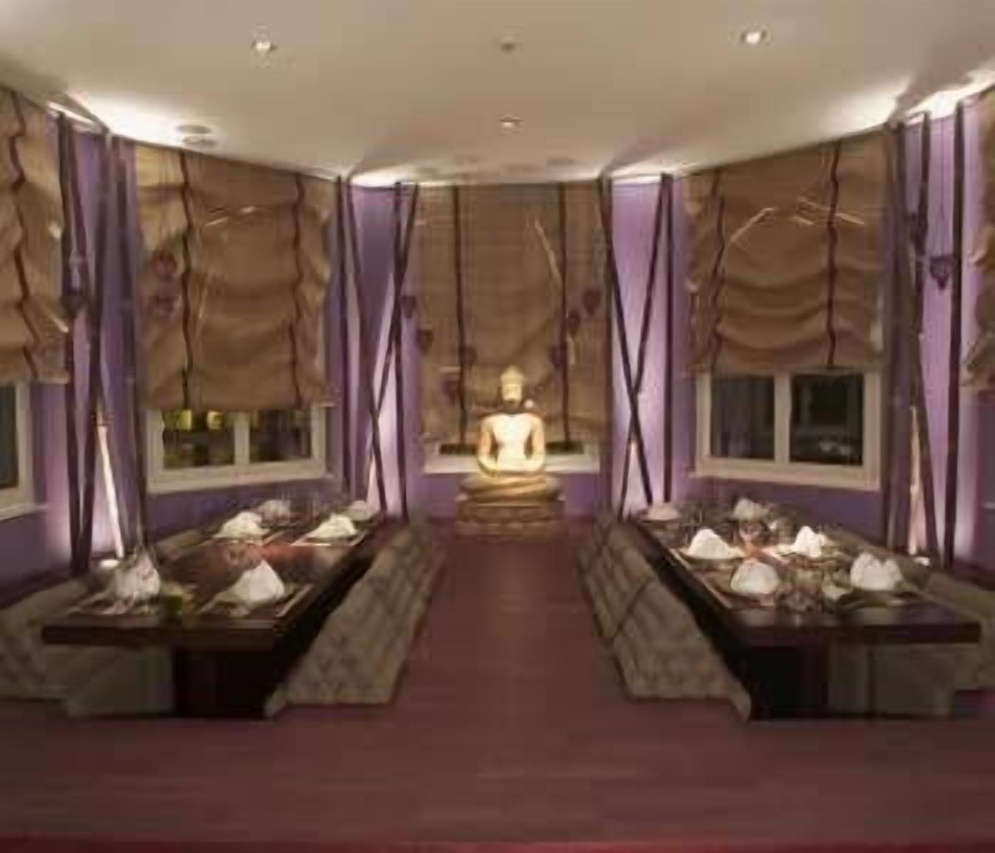 A room with a central Buddha statue, purple walls, and a patterned floor.
