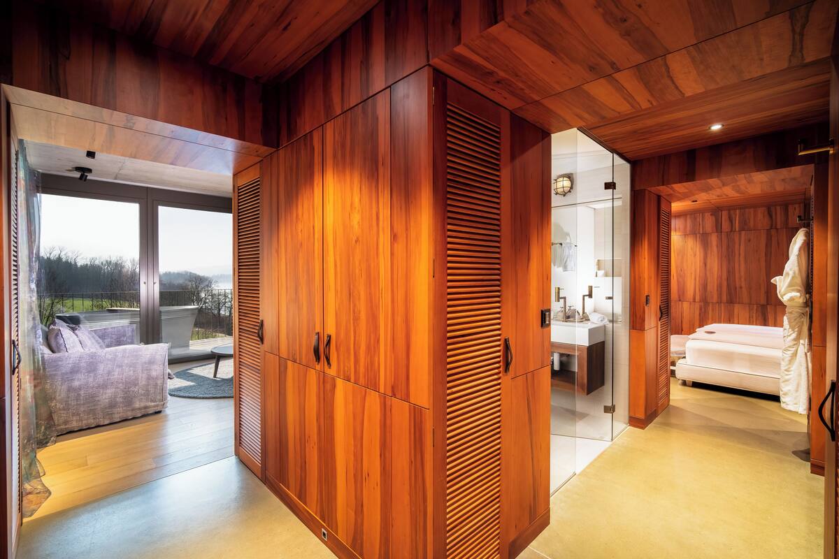 Ein modernes Interieur mit Holzwänden, einer Couch, einem Bett und einem Badezimmer mit Waschbecken und Spiegel.