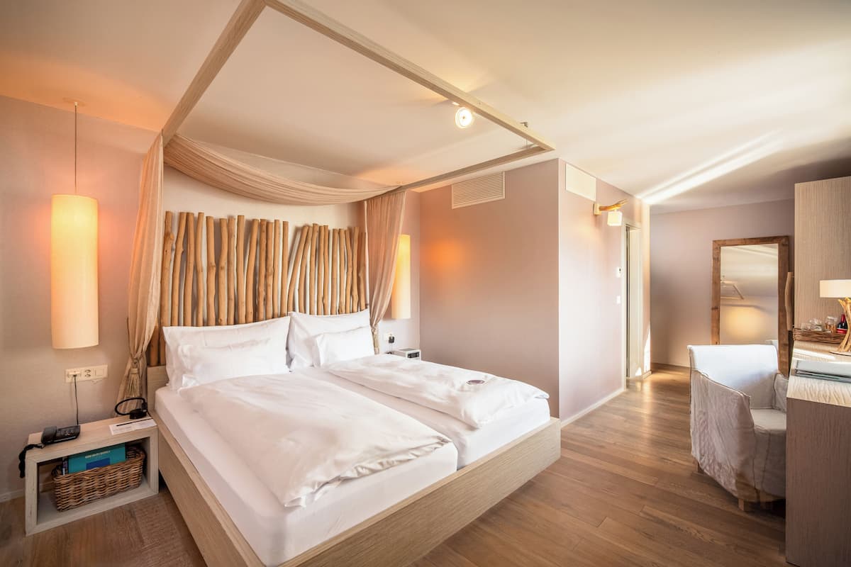 Ein modernes Hotelzimmer mit einem großen Bett, Nachttischen, einem Schreibtisch und einem Spiegel.