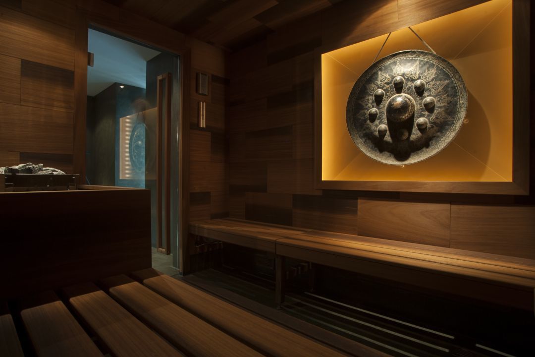 Una sauna con panche in legno e un elemento decorativo centrale in metallo.