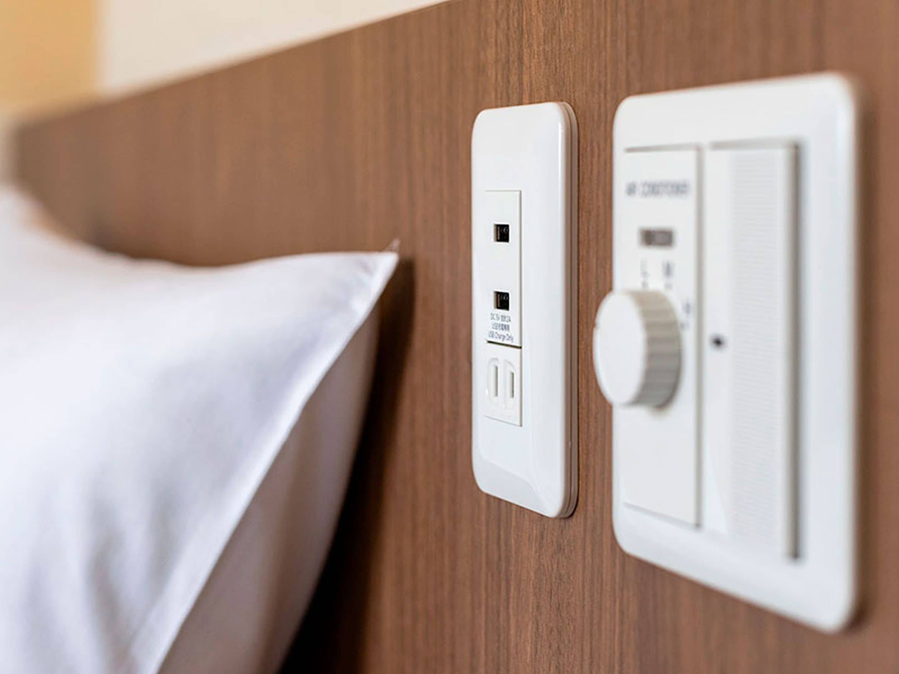 Un panel de control con un enchufe y un termostato sobre una pared de madera.