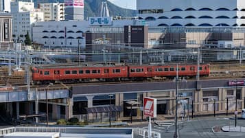 Un tren cruzando un puente en una zona urbana con edificios comerciales y un letrero grande de Daimaru.