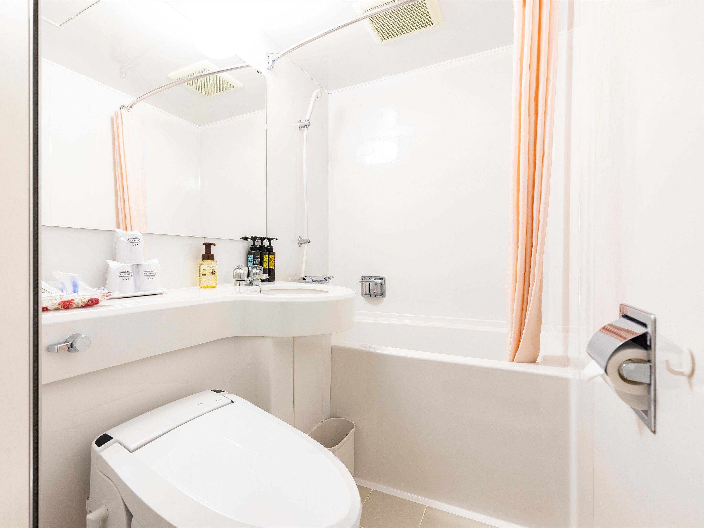 A modern bathroom with a white sink, mirror, and toilet. There is a shower with a glass door and a towel rack.