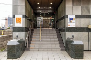Entrada de hotel con un letrero de Koko Stay, una escalera y un mapa que indica la ubicación del hotel dentro del edificio.