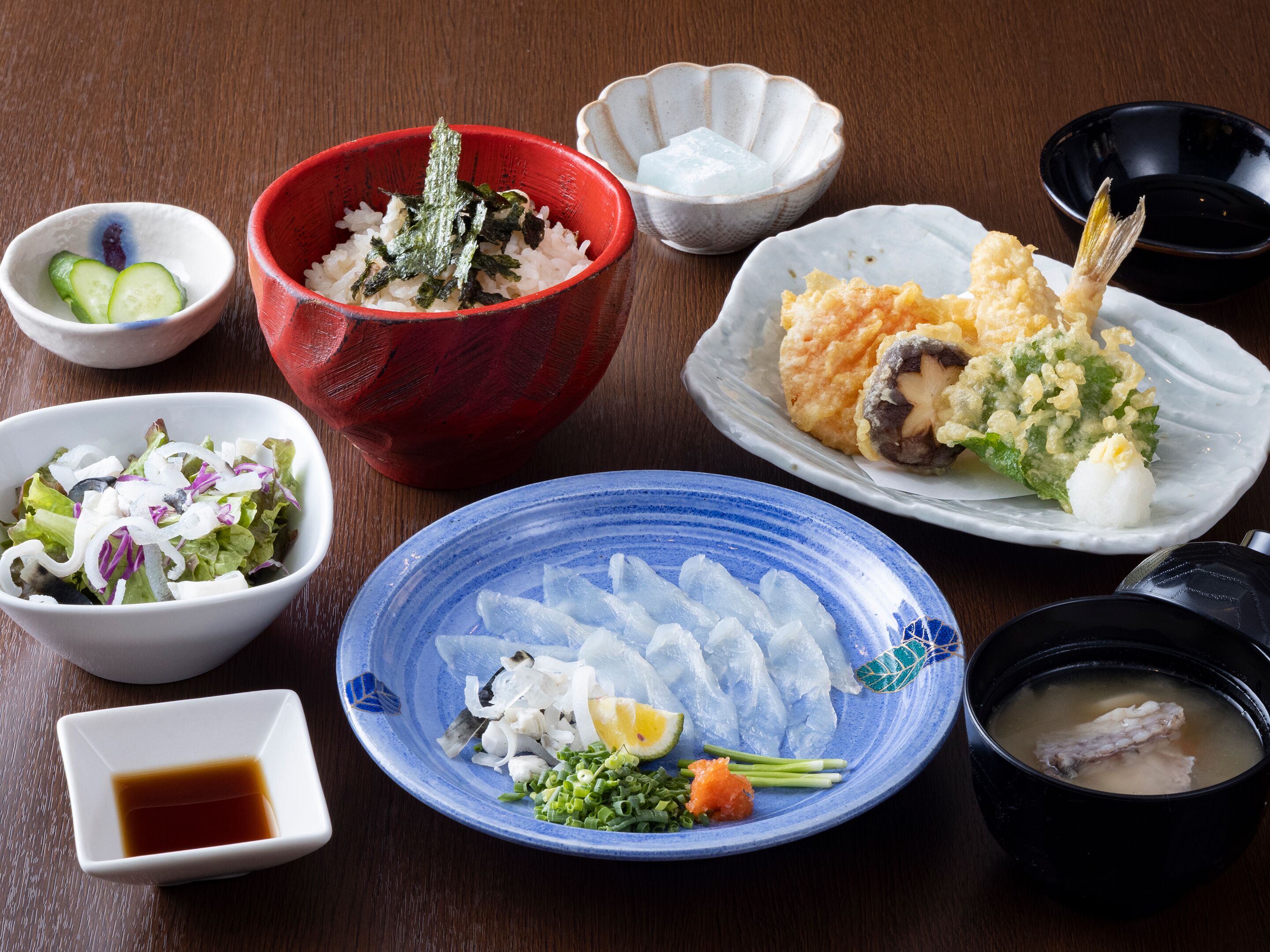 A variety of Japanese dishes including sushi, sashimi, and a bowl of soup.