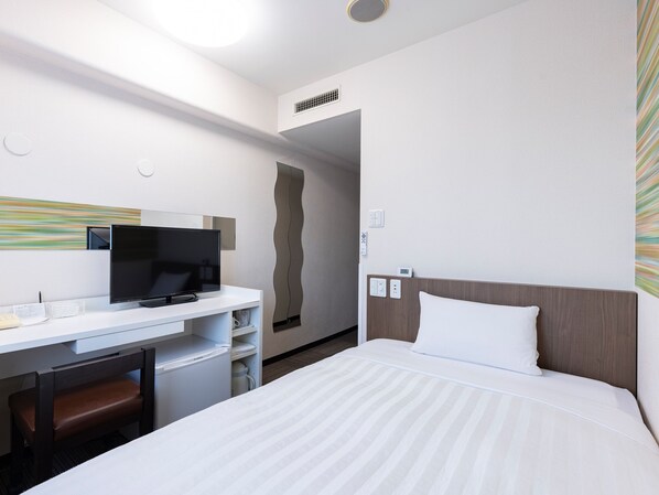 Una habitación de hotel con cama, escritorio con televisor, silla y baño.
