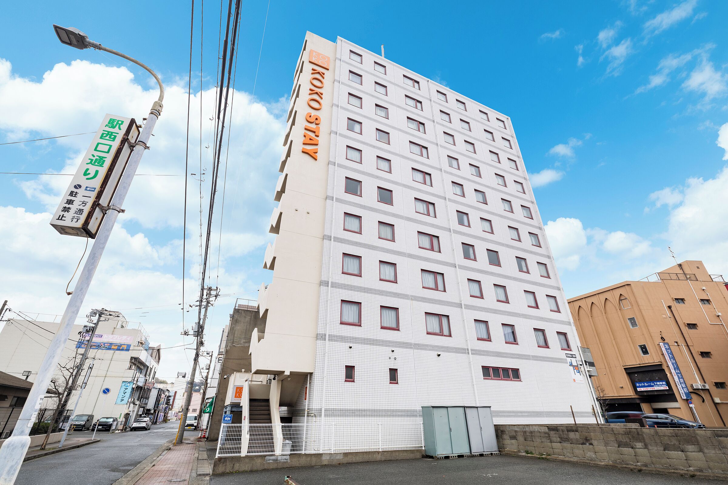 A multi-story hotel with a white facade and red window frames.