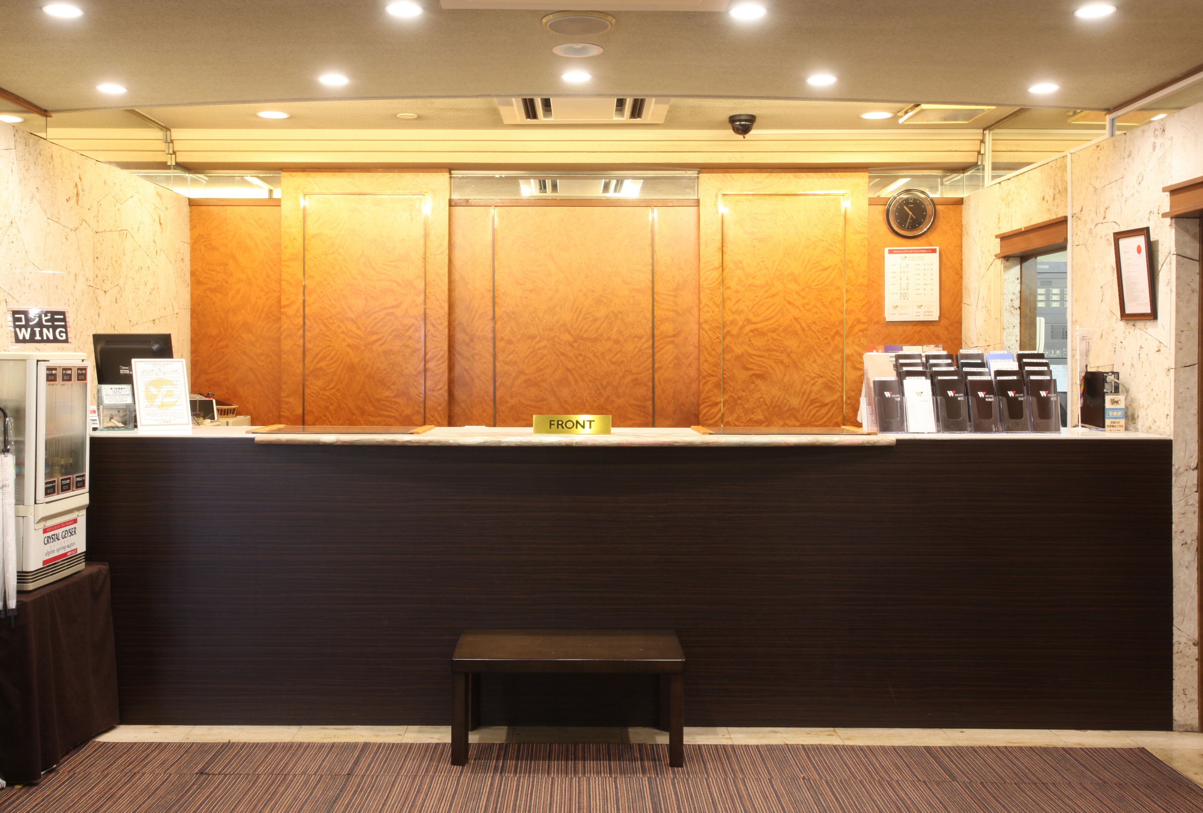 A reception area with a wooden reception desk, a clock, and a seating bench.