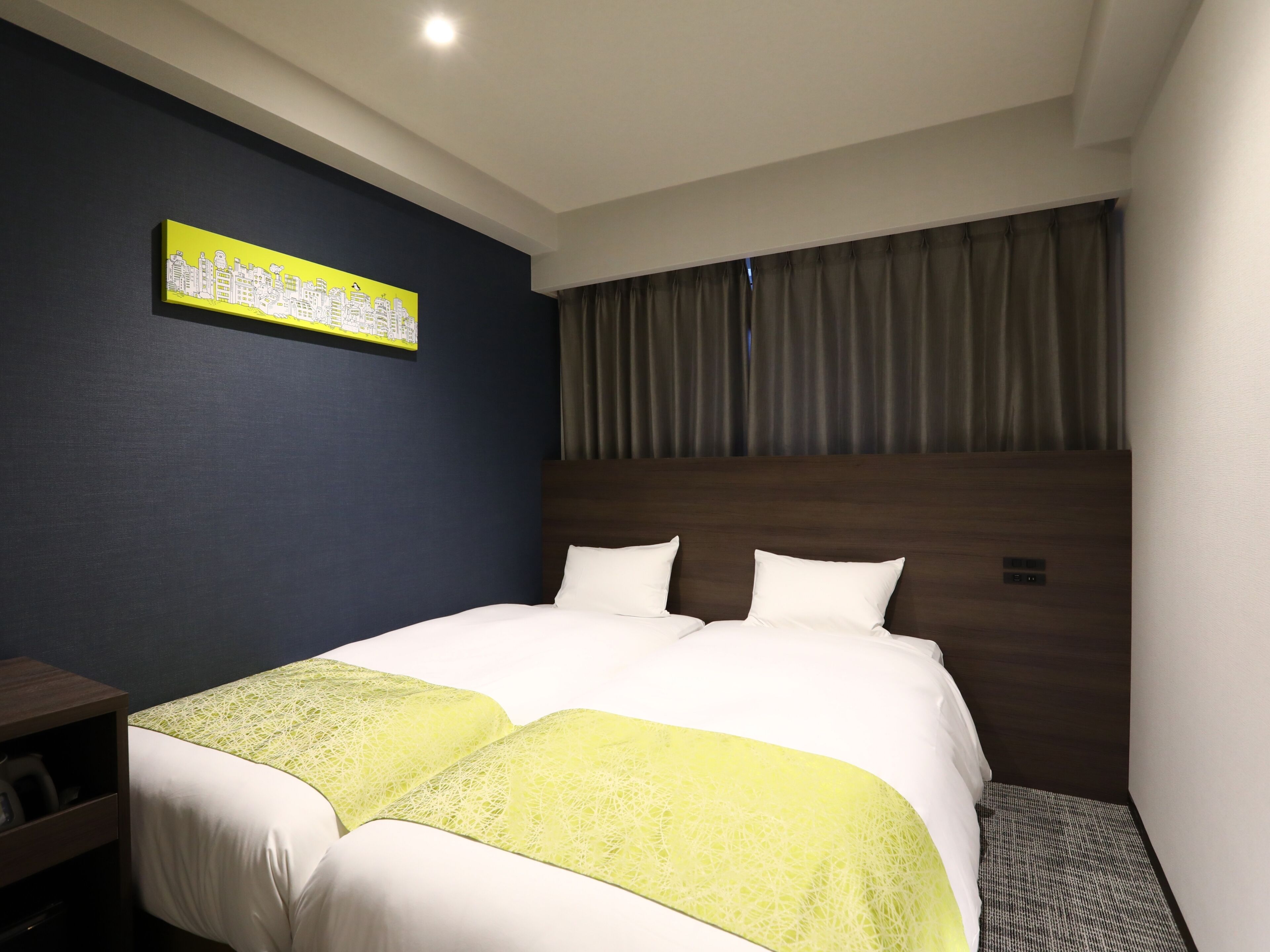 A hotel room with a large bed, a headboard, a nightstand, and a wall-mounted artwork.