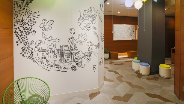 A modern interior with a cityscape mural, a green chair, and a patterned carpet. - KOKO HOTEL Ikebukuro East (Tokyo)