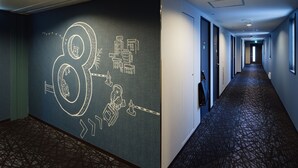 A hotel corridor with a large wall mural, a patterned carpet, and a long hallway with doors. - KOKO HOTEL Ikebukuro East (Tokyo)