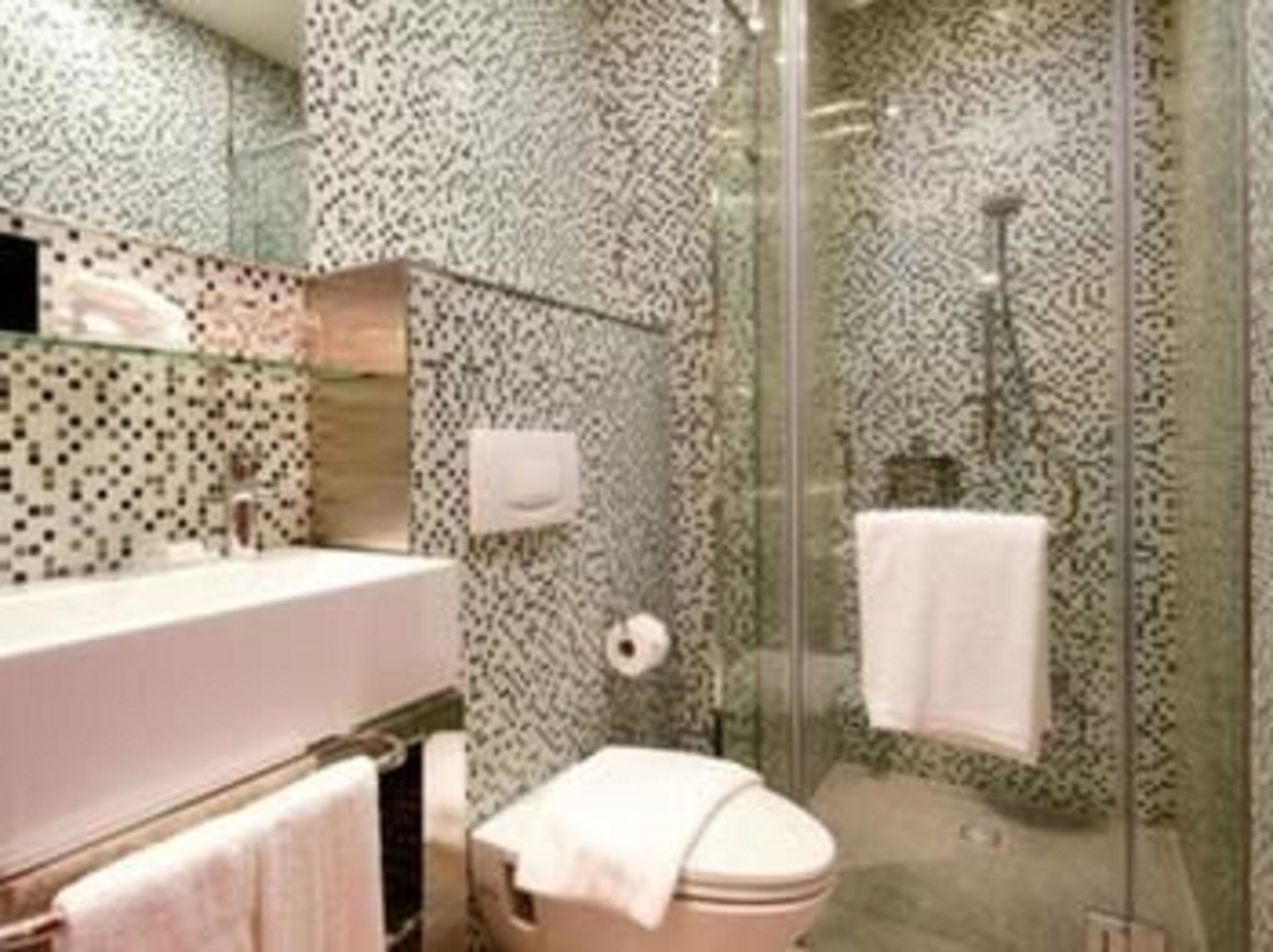 A bathroom with a glass shower enclosure, a white toilet, and a sink with a mirror.