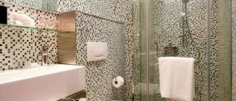 A bathroom with a glass shower enclosure, a white toilet, and a sink with a mirror.