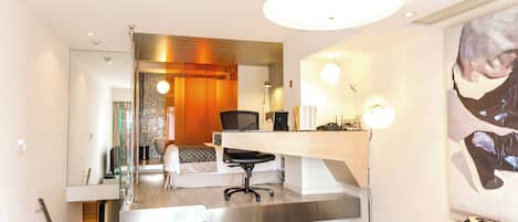 Una habitación de hotel moderna con cama, escritorio, silla y un espejo grande.