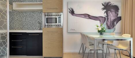A modern kitchen with a microwave, black cabinets, and a dining area with a glass table and chairs.