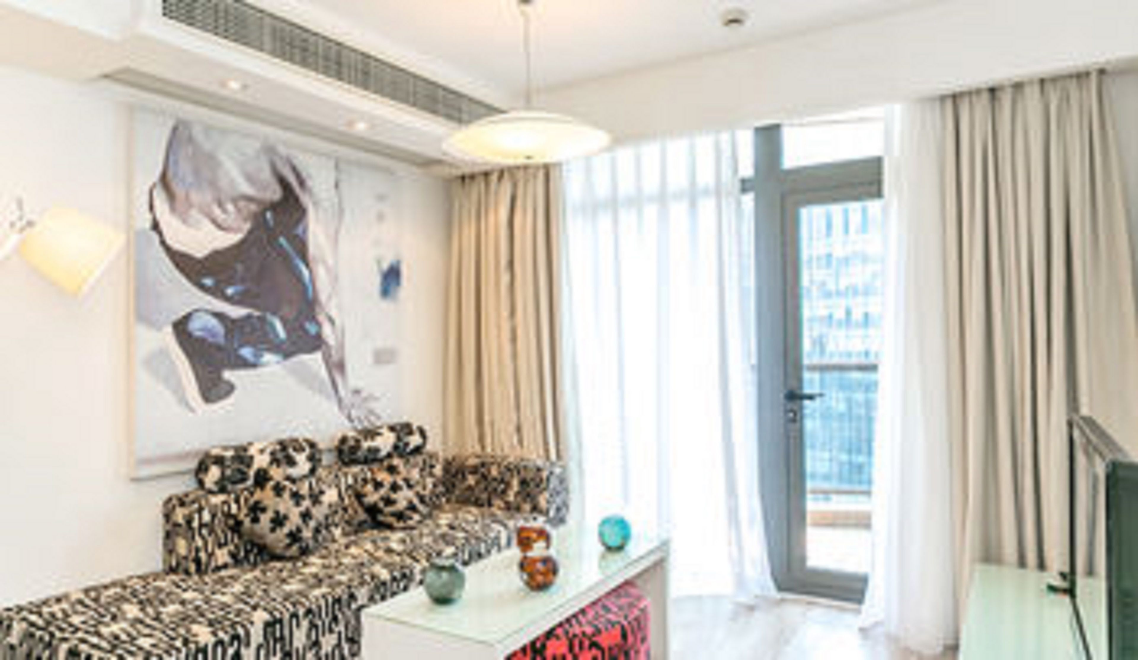 A modern living room with a patterned sofa, a white coffee table, and a large abstract painting on the wall.