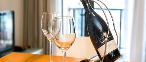 Une bouteille de vin est posée sur un présentoir, avec deux verres à côté, sur une table en bois.