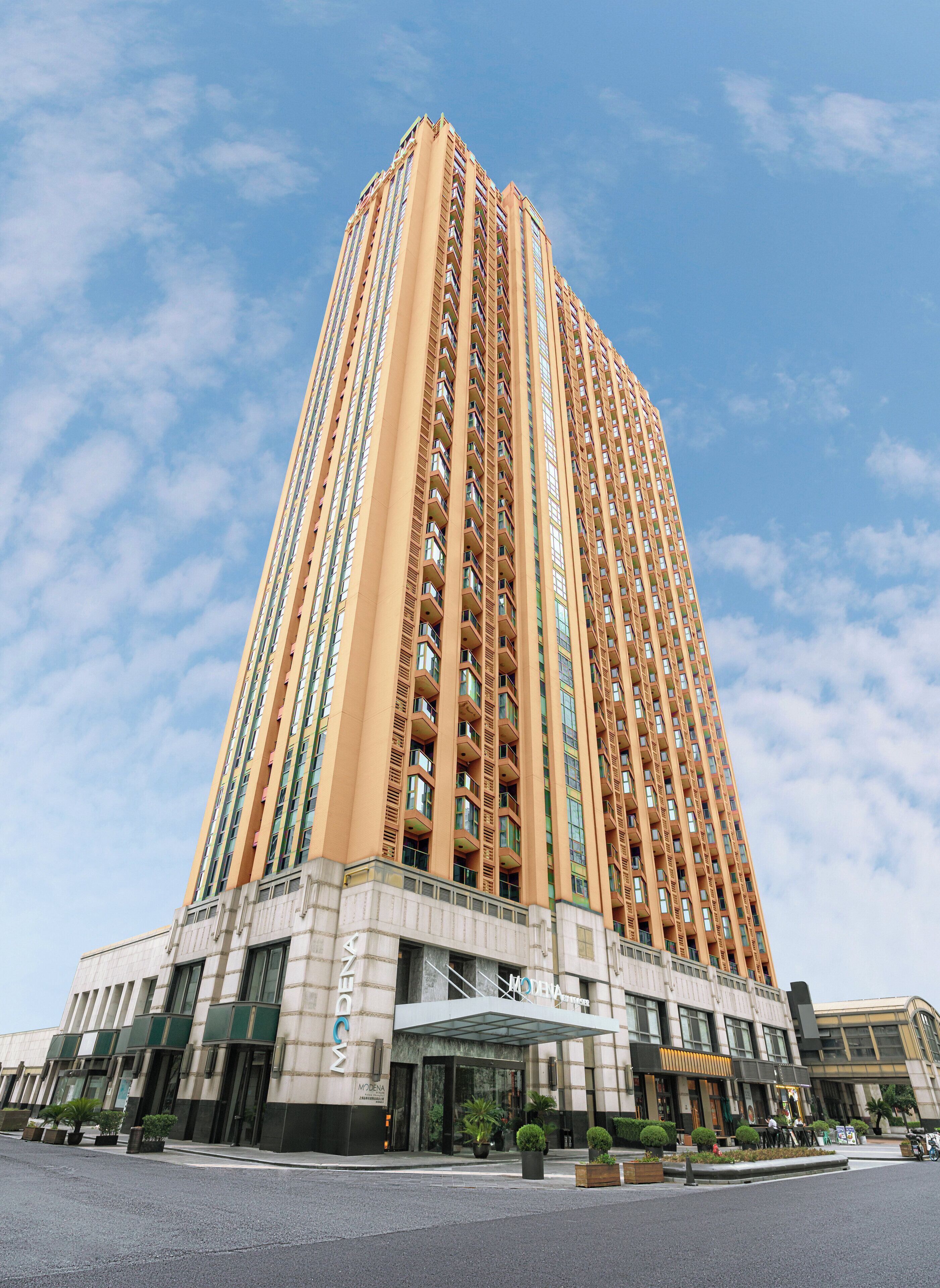 A tall, modern hotel with a prominent entrance and multiple balconies.