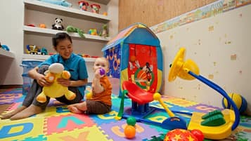 Children can play and learn in this vibrant playroom featuring a playhouse, slide, and ball pit.