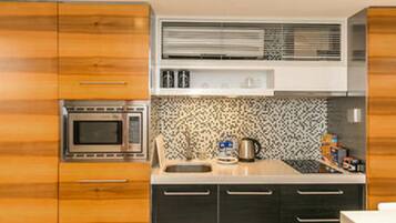 A modern kitchen with wooden cabinets, a microwave, a sink, and a patterned backsplash.