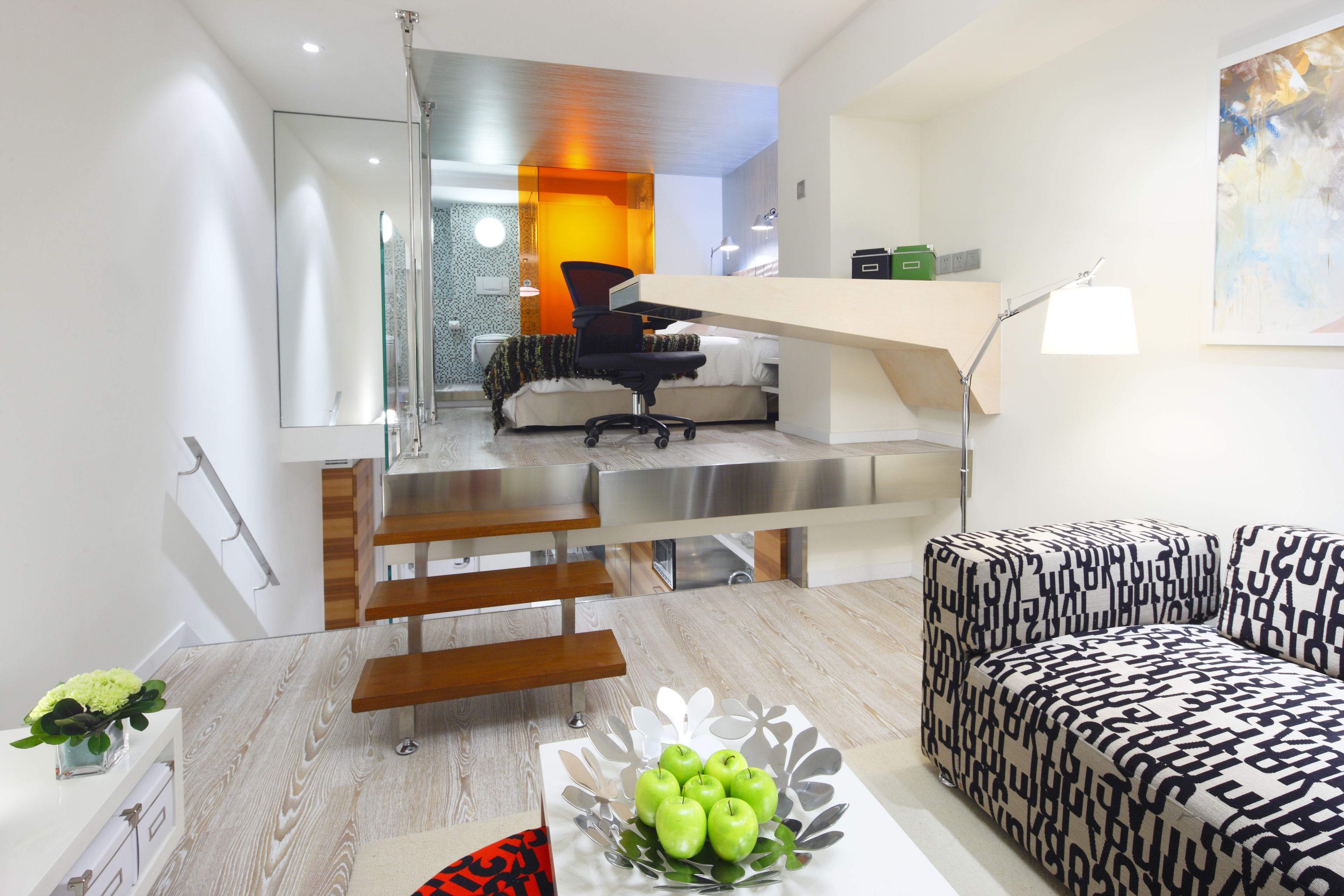 A modern living room with a staircase leading to a bedroom.