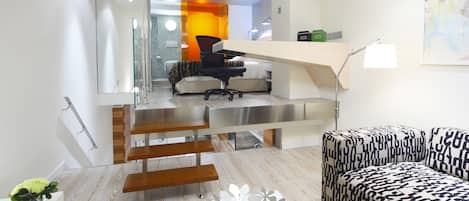 Un salon moderne avec un escalier menant à une chambre à coucher.