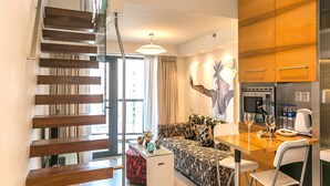 Un apartamento moderno con una escalera, un comedor, una cocina y una sala de estar con un sofá y un cuadro.